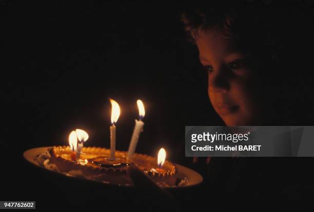 Enfant soufflant les bougies de son gâteau d'anniversaire.