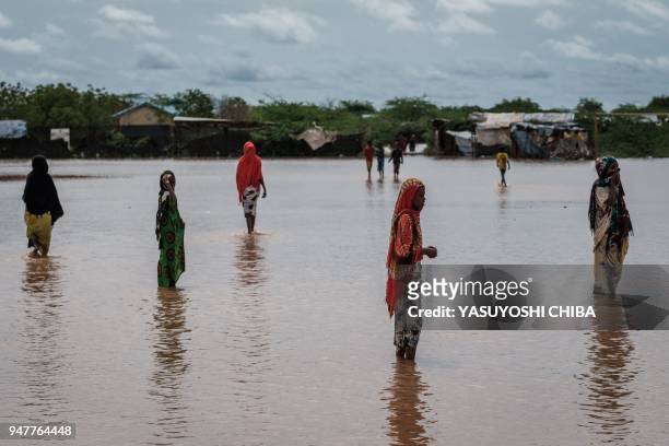 Refugees walk in floodwaters after a heavy rainy season downpour at the Dadaab refugee complex, in the north-east of Kenya, on April 17, 2018. The...
