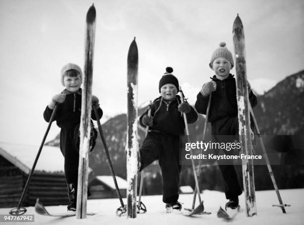 Trois jeunes garçons posent avec leurs skis en l'air.