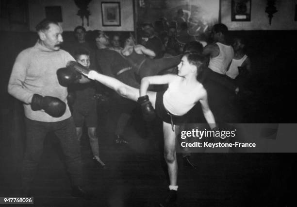 Un homme entraîne de jeunes garçons au combat de boxe.
