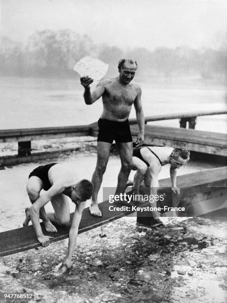 Des hommes en maillot de bain grattent la surface gelée d'un lac pour se baigner dedans en plein hiver.