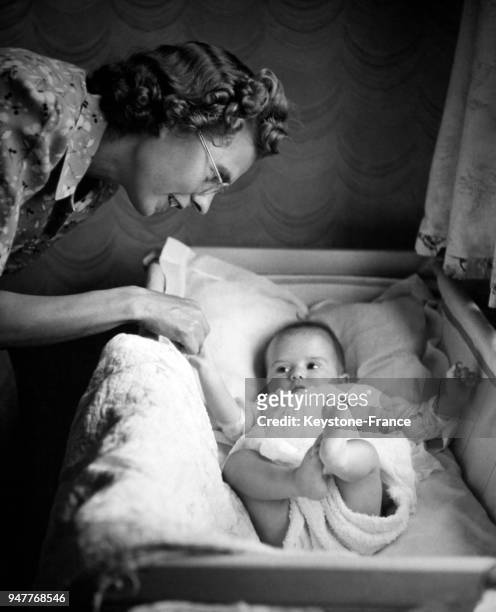 Une femme se penche sur le berceau de son nouveau-né.