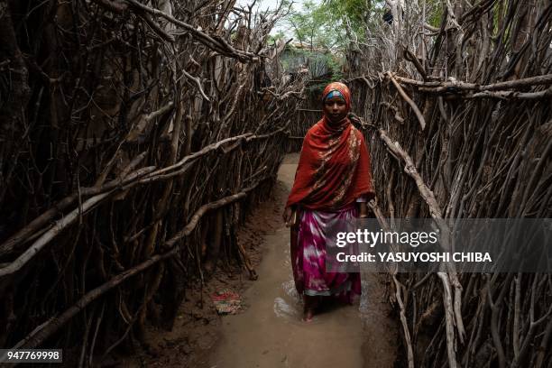 Woman walks along a flooded path between shelters after a heavy rainy season downpour at the Dadaab refugee complex, in the north-east of Kenya, on...