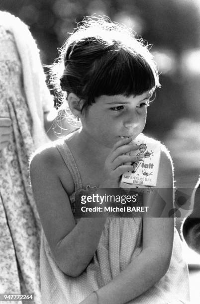 Petite fille buvant une brique de lait à la paille, en France.