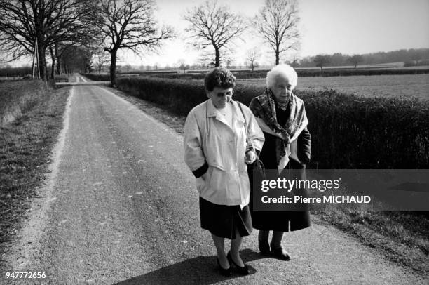 Bénévole d'une association d'aide au troisième âge se promenant avec une femme âgée en France.