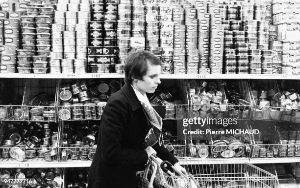 Femme dans le rayon boîtes de conserve d'un supermarché en France.