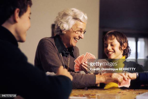 Enfants jouant aux cartes avec leur grand-mère, en France.