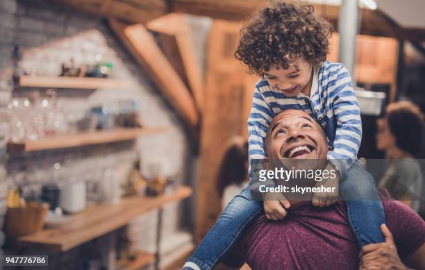 happy african american father having fun with his boy while carrying him on shoulders at home. - carrying on shoulders stock pictures, royalty-free photos & images