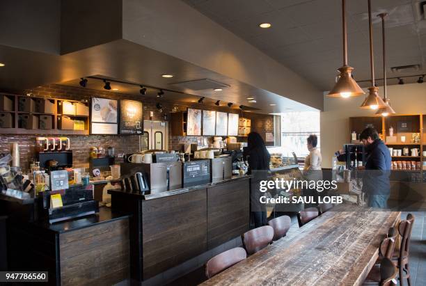 Customers line up inside a Starbucks Coffee shop in Washington, DC, April 17 following the company's announcement that they will close more than...