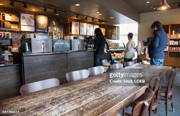 Customers line up inside a Starbucks Coffee shop in Washington, DC, April 17 following the company's announcement that they will close more than...