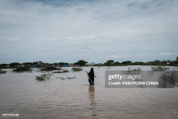 Young woman walks in floodwaters after a heavy rainy season downpour as they seek to fill sandbags at the Dadaab refugee complex, in the north-east...