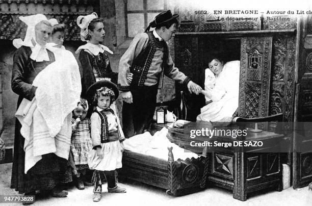 Famille bretonne en costume traditionnel avec femme dans un lit clos, en Bretagne, en France.