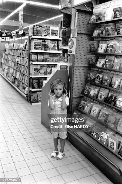 Enfant écoutant de la musique dans le rayon disque d'un supermarché en France.