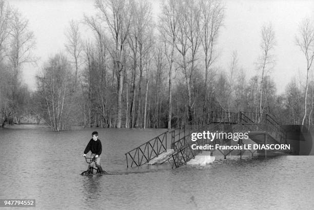 Enfant faisant du vélo dans un terrain inondé du Marais Poitevin, France.