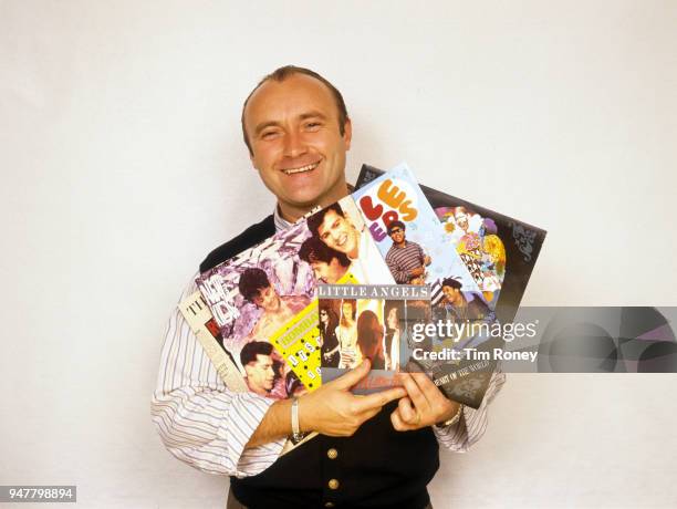 English drummer, singer-songwriter, record producer and actor Phil Collins of rock band Genesis, holding a portable radio and some records during a...