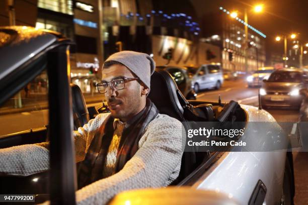 young man driving car through city at night - arab driving stock-fotos und bilder