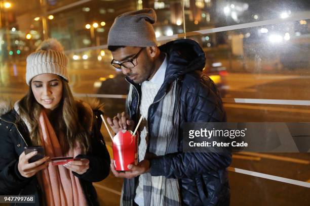 young couple in bus stop paying for online shopping with card - carte bancaire voiture photos et images de collection