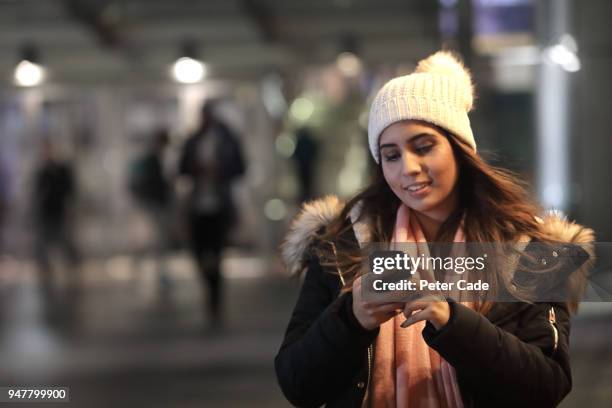 woman looking at phone in city at night - devon winer stock-fotos und bilder