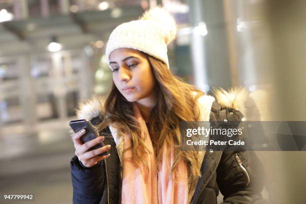 woman looking at phone in city at night - esperar alguém imagens e fotografias de stock