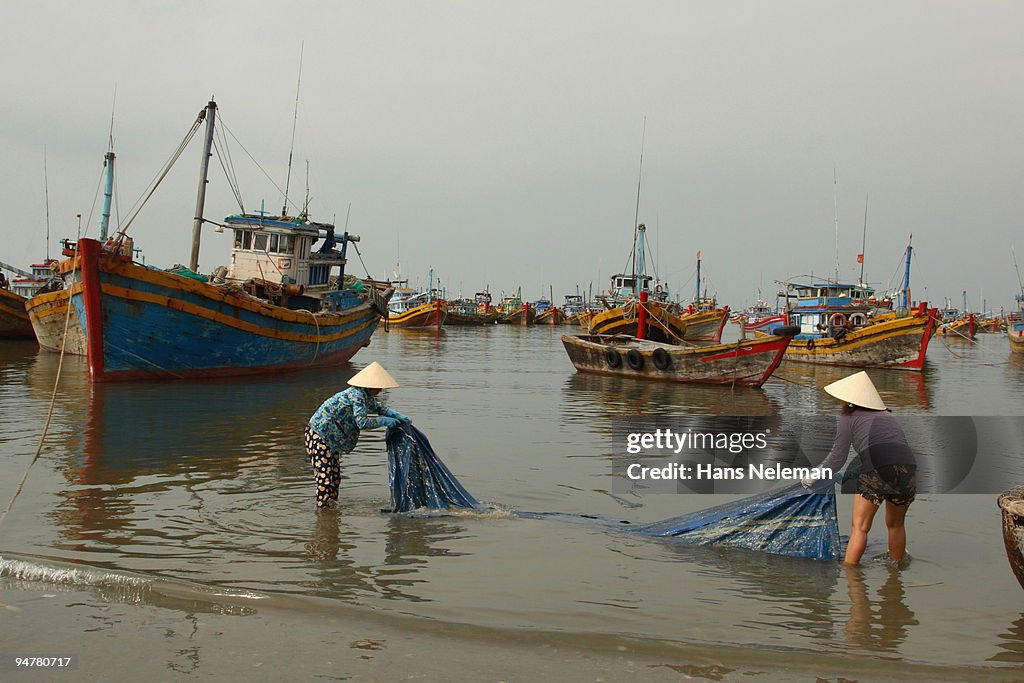 Two women washing canvas at a harbor, Vietnam