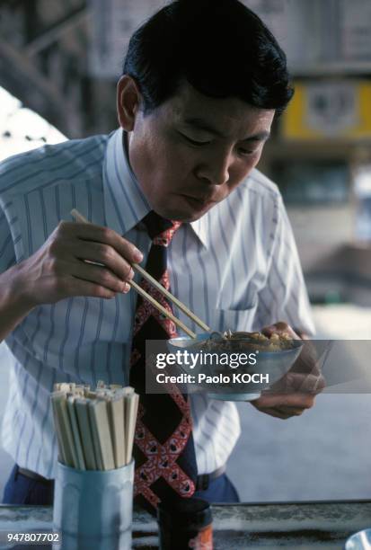 Employé japonais mangeant des nouilles dans un yatai au Japon.