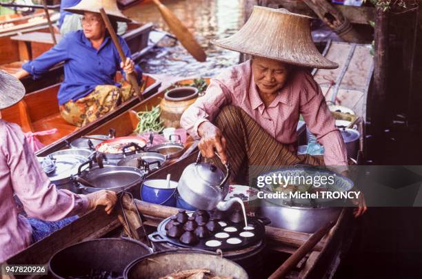 Marchande servant le thé dans un marché flottant en Thaïlande.