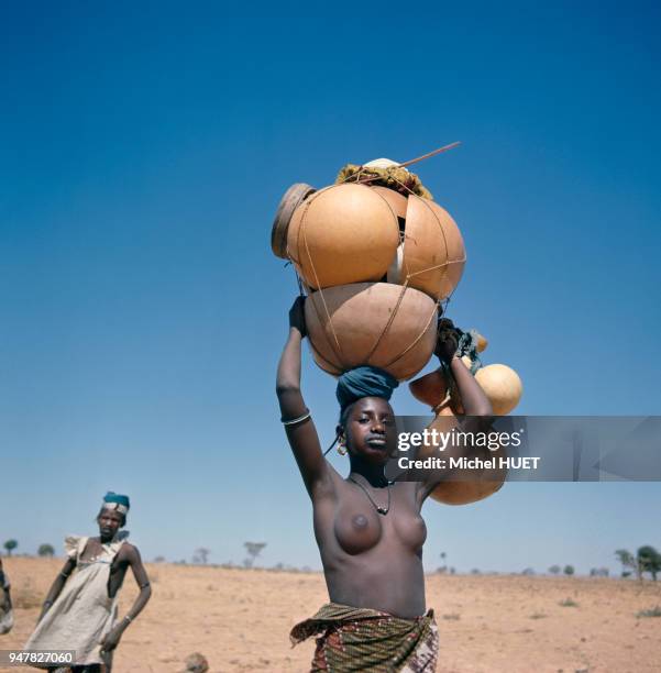 Jeune femme portant des calebasses sur la tête au Mali.