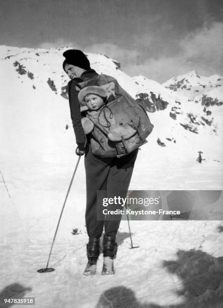 Femme sur des skis porte son enfant dans un sac à dos dans les montagnes en Autriche.