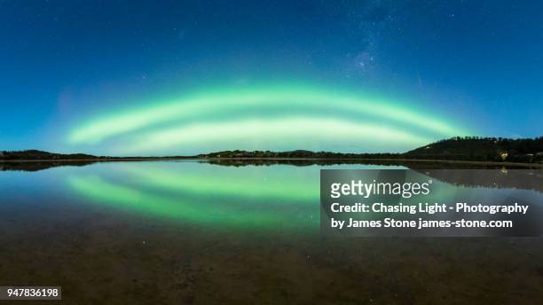 double green arc of aurora with reflection in water at blue hour - aurora australis stock pictures, royalty-free photos & images