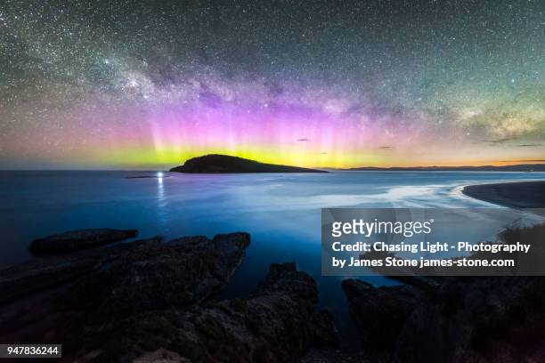 colourful display of the aurora australis over an island in the ocean at blue hour - aurora australis stock pictures, royalty-free photos & images