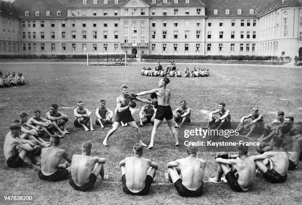 De jeunes hommes allemands rassemblés en cercle s'affrontent en combat de boxe singulier, circa 1930 en Allemagne.