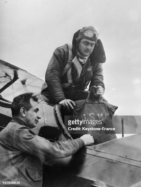 Un capitaine d'aviation prend le sac postal à bord de l'avion de chasse conduit par un pilote militaire, aux Etats-Unis en 1934.