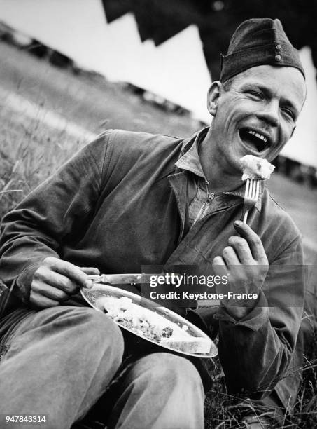 Un jeune soldat, tout sourire, mange pendant sa pause déjeuner lors des manoeuvres dans la région de l'Est-Anglie, au Royaume-Uni circa 1930.