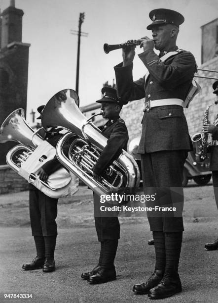 Le soldat le plus grand du 2e bataillon du Royal Sussex Regiment jouant de la clarinette au côté de ses compagnons qui semblent bien petits avec...