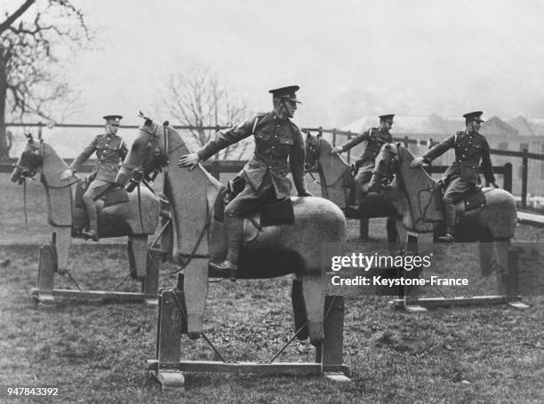 Des recrues de cavalerie britanniques apprennent à monter à cheval sur des des chevaux de bois mécaniques, au Royaume-Uni en mars 1935.