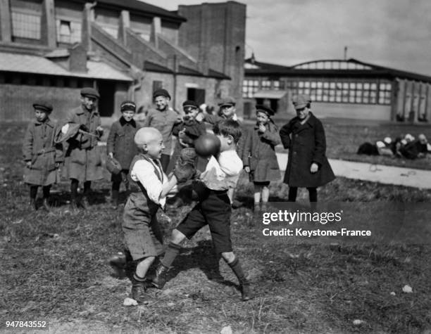 De jeunes garçons anglais jouent au football près d'un lotissement, circa 1950 au Royaume-Uni.
