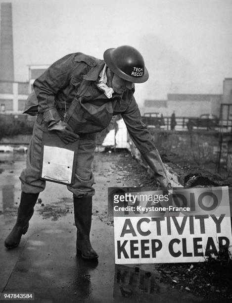 Un membre de la défense civile'Air Raid Precautions' pose une pancarte annonçant un danger de radio-activité, au Royaume-Uni circa 1950.