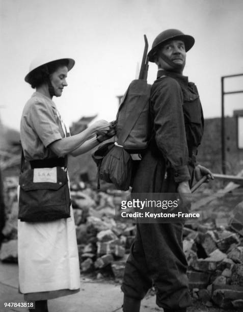 Une infirmière de la Croix Rouge ajuste au dos d'un officier le nouveau sac de protection en cas de guerre nucléaire pendant un exercice, au...