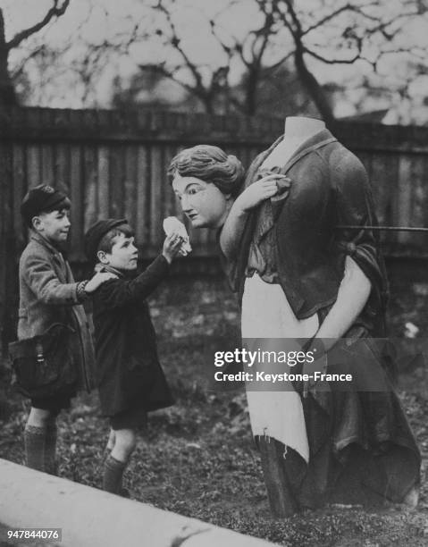 Deux petits enfants regardent une statue de femme portant sa tête sous le bras, au Royaume-Uni en mars 1935.