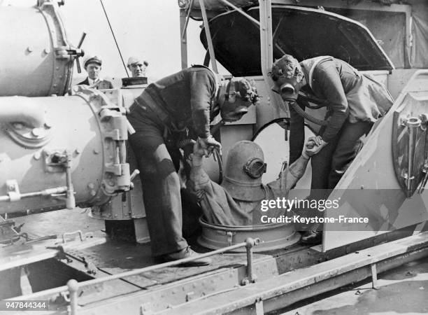 Des marins portant des masques à gaz font une démonstration d'un scaphandre d'un type nouveau à bord du cuirassé 'Versatile' au large des côtes...