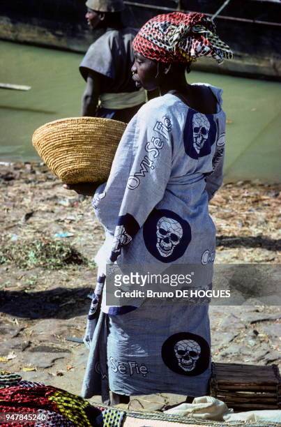 Une femme habillée d'un boubou à têtes de mort dans le port de Mopti sur le fleuve Niger. Mali en Décembre 1981.