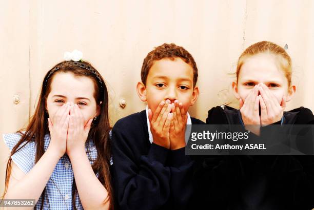 Eltam, garçon et filles dans la cour de récréation mettant leurs mains devant la bouche.