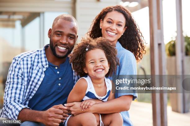 Young black family embracing outdoors and smiling at camera