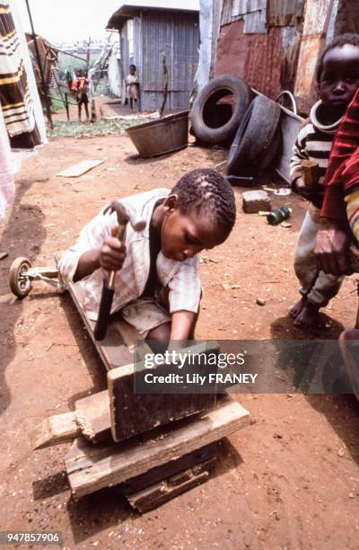 Enfant se fabriquant un jouet avec des planches au Mali, en 1987.