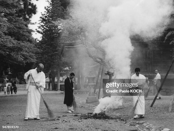 Moines balayant et brûlant les feuilles mortes dans la cour du monastère Konpon Daito, sur le mont Koya, circa 1970, Japon.