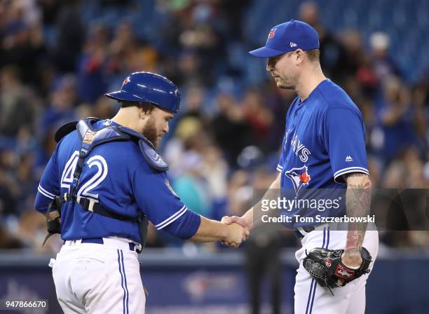 John Axford of the Toronto Blue Jays celebrates their victory with Russell Martin during MLB game action against the Kansas City Royals at Rogers...