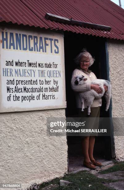 Fileuse de tweed de Harris tenant un agneau, sur l'île de Lewis et Harris, en 1978, en Ecosse, Royaume-Uni.