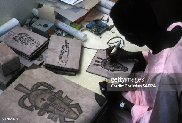 Artisan faisant de la pyrogravure sur cuir au Burkina Faso, en mars 1987.