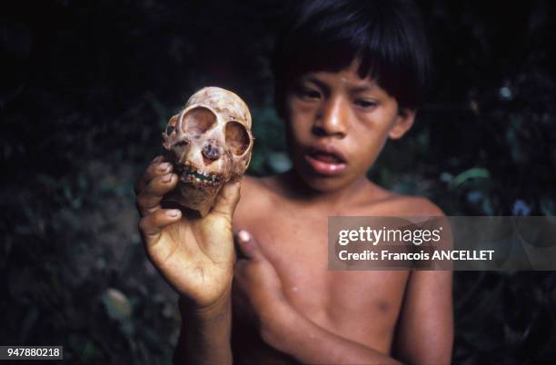 Enfant indien Waorani présentant un crâne de singe en Equateur, en 1991.
