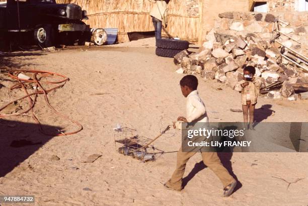 Enfant jouant avec une voiture bricolée à partir de boîtes de conserve et de fils de fer, en Algérie, en 1986.